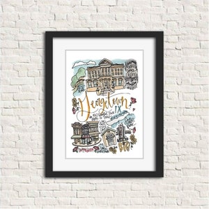 May include: A framed watercolor print featuring the word "Georgetown" in gold script. The artwork depicts various buildings and landmarks, including a university and shops, with the text "the most beautiful town in Texas". The print is framed in a black frame.