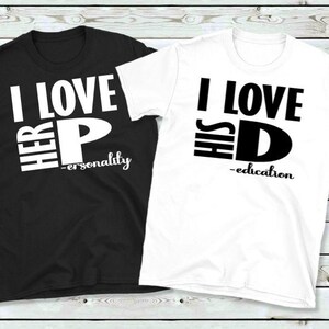 May include: Two t-shirts, one black and one white, with bold black text. The black shirt reads "I LOVE HER P - personality" and the white shirt says "I LOVE HIS D - education". Both shirts have a crew neck.