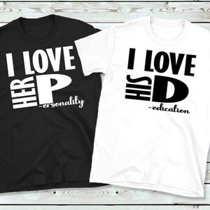 May include: Two matching t-shirts, one black and one white. The black shirt has the text "I LOVE HER P" with "-personality" below. The white shirt says "I LOVE HIS D" with "-education" below. Both shirts have a crew neck.