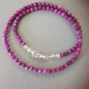 May include: A delicate necklace made of small, faceted, purple gemstone beads. The necklace has a silver clasp.