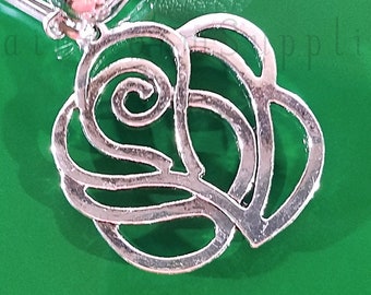 May include: Silver-toned metal charm in the shape of a stylized heart with a swirl design. The charm is on a green background.