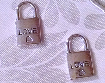 May include: Five silver-toned miniature padlocks with the word "LOVE" and a heart engraved on each. A silver-toned skeleton key with a heart-shaped bow at the top.