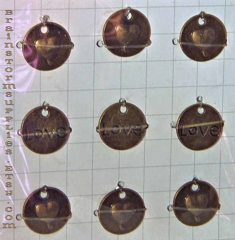 May include: Nine oval-shaped metal charms with a hole at the top. Three charms feature a heart design, three charms feature the word "Love", and three charms feature a heart design.