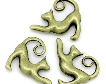 May include: Three antique gold-toned metal cat charms with curled tails. The charms are in various poses, including sitting, standing, and curled up.