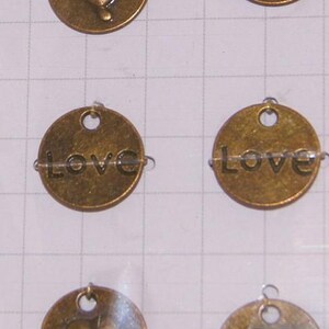 May include: Six gold-toned metal charms with a heart or the word "LOVE" engraved on them. Each charm has a small loop at the top for attaching to a necklace or bracelet.