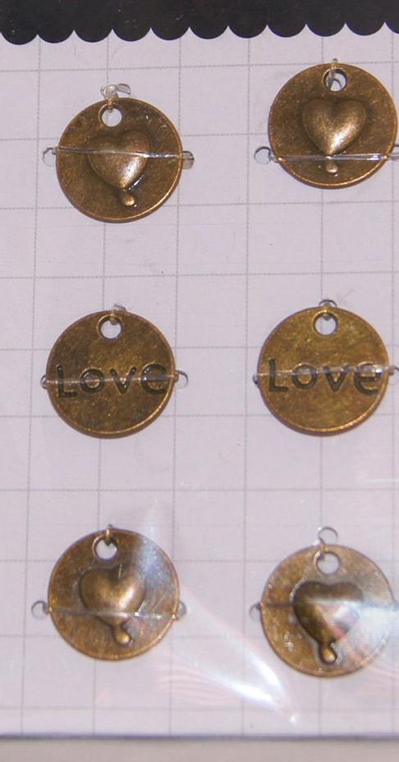 May include: Six gold-toned metal charms with a heart or the word "LOVE" engraved on them. Each charm has a small loop at the top for attaching to a necklace or bracelet.
