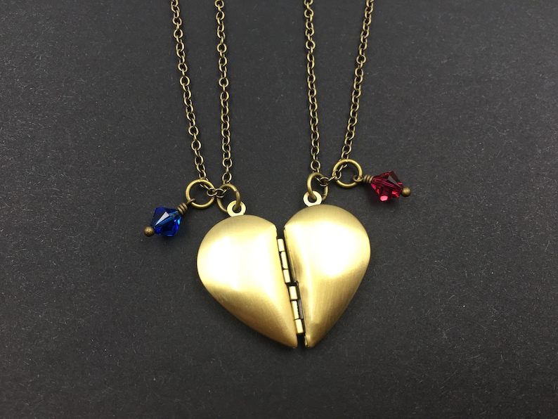 May include: Two gold necklaces with heart-shaped lockets that open. Each locket has a small blue or red crystal charm.