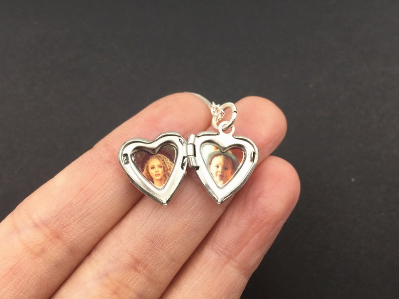 Puede incluir: Collar con dije de plata en forma de coraz&oacute;n con dos compartimentos separados, cada uno con una foto de una persona. El dije est&aacute; abierto, revelando las fotos en el interior.