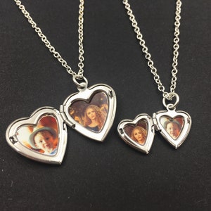 Puede incluir: Dos collares de plata con colgantes en forma de coraz&oacute;n. El colgante m&aacute;s grande tiene una foto de una mujer con el pelo largo y rizado, y el colgante m&aacute;s peque&ntilde;o tiene una foto de un ni&ntilde;o.