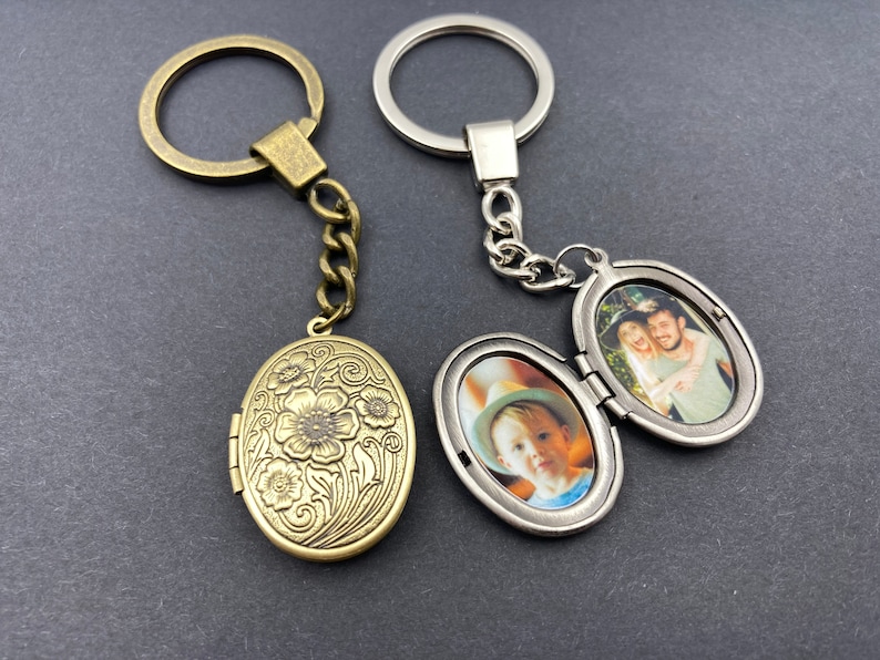 Puede incluir: Dos llaveros con medall&oacute;n de foto ovalado. Uno es plateado con una foto de un ni&ntilde;o peque&ntilde;o. El otro es de bronce con un dise&ntilde;o floral grabado.