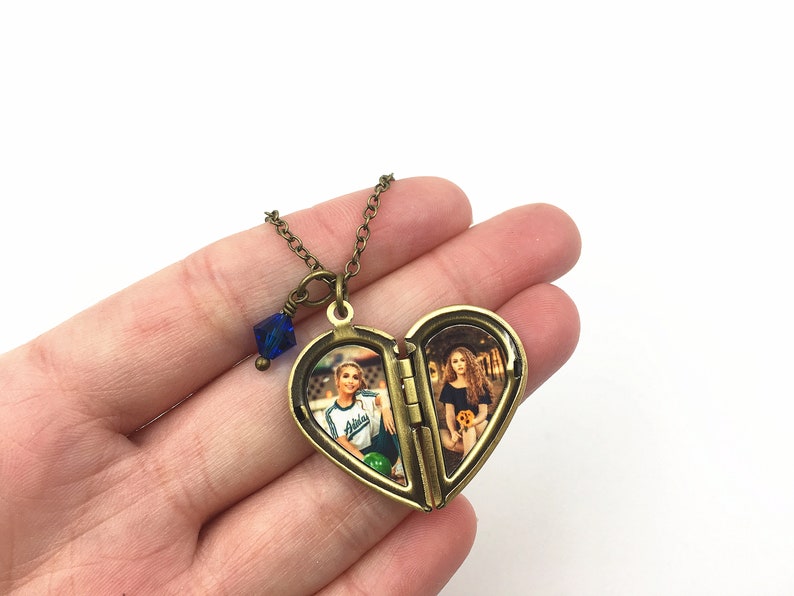 May include: A heart-shaped locket necklace with a blue crystal charm. The locket opens to reveal two photos of people.