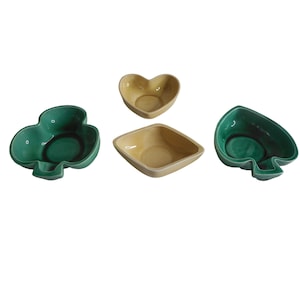May include: Set of four ceramic bowls in green and yellow. The bowls are shaped like a heart, a square, and two playing card suits: a spade and a clover.