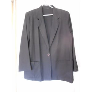 Può includere: Un blazer nero con una chiusura a bottone singolo e due tasche. Il blazer ha una vestibilità classica e sartoriale.