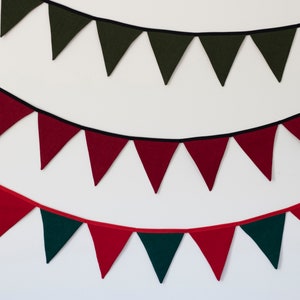 May include: A festive garland with alternating red and green felt triangle flags. The garland is strung with black and red twine.