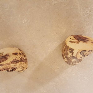 Könnte beinhalten: Zwei natürliche Holz-Wandhaken mit einem hellbraunen und dunkelbraunen Holzmaserungsmuster.