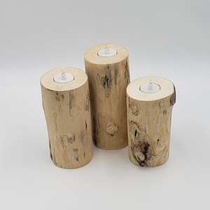 Puede incluir: Tres portavelas de madera con un acabado de madera natural. Cada portavelas tiene una abertura circular para una vela de té.