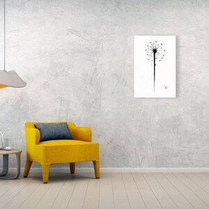 May include: A minimalist art print featuring a black dandelion silhouette against a white background. The artwork is displayed on a wall in a modern living room setting, alongside a yellow armchair and a side table.