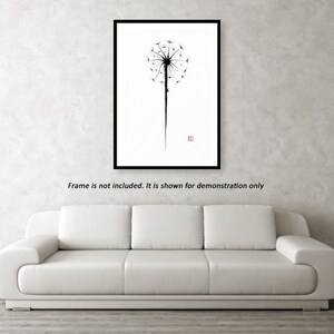 May include: Black framed art print featuring a minimalist dandelion design. The artwork is in black ink on a white background, with a long stem and a small red square in the corner. The text "Frame is not included. It is shown for demonstration only" is below the frame.