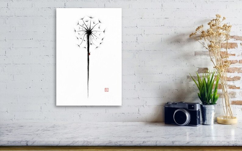 May include: A minimalist black and white dandelion art print. The artwork features a detailed dandelion seed head with a long stem and a small red accent. The print is displayed on a white wall, creating a striking contrast.