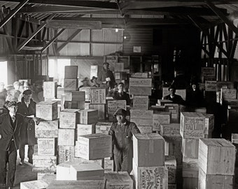 May include: A black and white photograph of a warehouse interior filled with stacked wooden crates labeled with various distillery names like Old Taylor, Old Jordan, and Cascade. Several individuals in period clothing stand among the boxes.