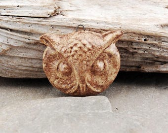 May include: A brown ceramic owl pendant with a textured surface. The owl has large, round eyes and a small beak.