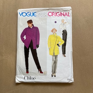 May include: Vogue Paris Original sewing pattern for a jacket and pants by Chloé. The pattern features two models, one wearing a purple jacket and black pants, and the other wearing a yellow jacket and gray pants. The pattern number is 2323.