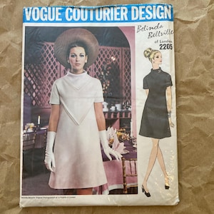 May include: Vintage Vogue Couturier Design sewing pattern featuring a white dress with a V-neckline and short sleeves. The pattern is by Belinda Bellville of London and the pattern number is 2205.