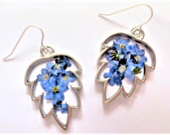 May include: Silver leaf-shaped earrings with forget-me-not flowers pressed inside.