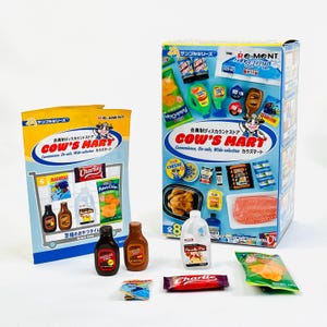 May include: Miniature grocery store items, including a carton, a shopping cart display, and individual food products. The packaging features the "COW'S MART" logo and Japanese text. The items include bottles, a candy bar, and a bag of chips.
