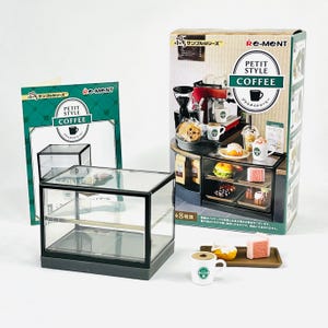 Può includere: Un playset di un negozio di caffè in miniatura con una vetrina in vetro, tazze di caffè, pasticcini e una macchina per il caffè. La scatola recita "PETIT STYLE COFFEE" e "Re-Ment". Il set include una piccola vetrina con due ripiani.