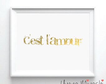 May include: A white framed print with the text "C'est l'amour" in gold foil lettering. The artist's signature, "Uyeno Miyoshi", is in the bottom right corner.
