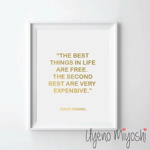May include: A white framed print with a gold quote by Coco Chanel that reads "THE BEST THINGS IN LIFE ARE FREE. THE SECOND BEST ARE VERY EXPENSIVE."