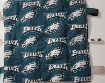 Puede incluir: Un juguete sensorial para bebés de tela verde con un patrón de los Philadelphia Eagles. El juguete tiene múltiples lazos y etiquetas de tela para que el bebé explore.
