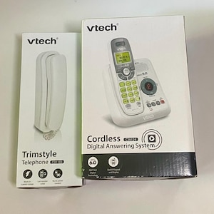 May include: Two white Vtech telephones are displayed. One is a Trimstyle Telephone CD1103, and the other is a Cordless Digital Answering System CS6124. The cordless phone has a backlit keypad and display. Both are in their original packaging.