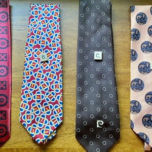 May include: Four different patterned neckties, labeled A, B, C, and D. Tie A is red with a black and white geometric pattern. Tie B is red, blue, and white with a geometric pattern. Tie C is brown with white polka dots. Tie D is pink with a blue and white pattern.