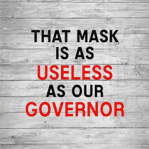以下が含まれることがあります： 灰色の木製の背景に「That mask is as useless as our governor」というテキストが書かれた看板です。
