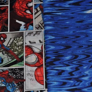 Puede incluir: Una tela azul y negra con un patr&oacute;n ondulado. La tela est&aacute; impresa con una imagen de estilo c&oacute;mic de Spiderman en rojo y azul.