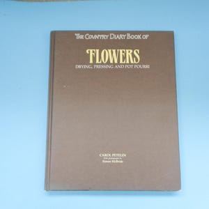 May include: The Country Diary Book of Flowers: Drying, Pressing and Pot Pourri by Carol Petelin with photographs by Simon McBride. A brown book with gold lettering on the cover.