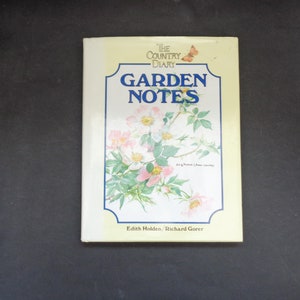 Peut inclure: Un livre intitulé "Garden Notes" de la série "The Country Diary". La couverture présente une illustration florale de roses roses et de feuilles vertes, avec le titre en lettres bleues. Les auteurs, Edith Holden et Richard Gorer, sont nommés en bas.
