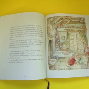 May include: An open book with colorful illustrations. The right page shows a detailed drawing of a bathroom with a bathtub, curtains, and small figures. The left page contains printed text. The book is on a yellow surface.