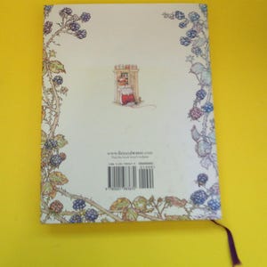 May include: A book cover with a whimsical illustration. The cover features a drawing of a mouse in a red dress, framed by a border of blackberries and leaves. The website www.fireandwater.com is visible.