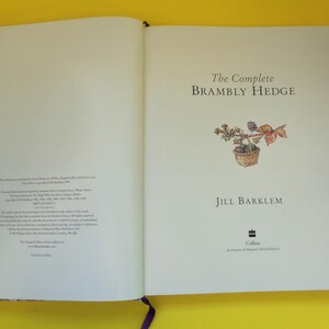 May include: Open book with the title "The Complete Brambly Hedge" by Jill Barklem. The cover features a watercolor illustration of a basket with berries and leaves. The book is open to a double-page spread.