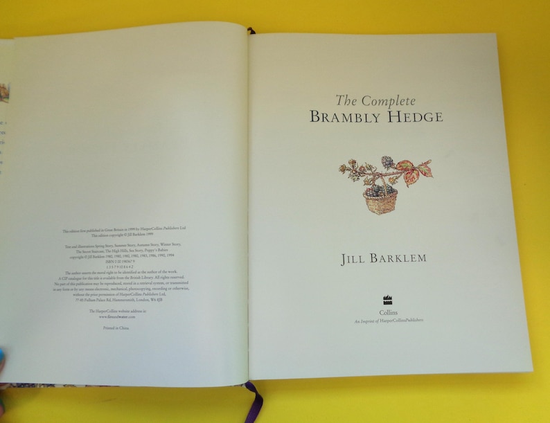 May include: Open book with the title "The Complete Brambly Hedge" by Jill Barklem. The cover features a watercolor illustration of a basket with berries and leaves. The book is open to a double-page spread.