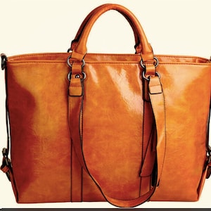May include: A large, orange leather tote bag with a top handle and a long shoulder strap. The bag has a zipper closure and a tassel on the strap.