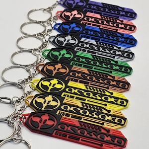 May include: A collection of colorful keychains with silver key rings. Each keychain features a unique design with the word "OSOSOKO" and a logo. The keychains are in various colors, including red, yellow, and green.