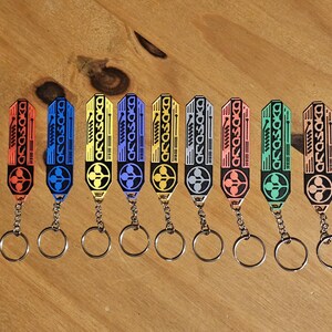 May include: A collection of keychains in various colors, including red, blue, yellow, and green. Each keychain features a rectangular design with the word "ASOSOKO" and a circular emblem, attached to a silver keyring.