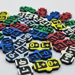 Può includere: Una collezione di colorati pezzi di gioco con basi nere e numeri e simboli bianchi, rossi, verdi, blu e gialli in rilievo. I pezzi presentano numeri come -1, 0 e +1, e simboli come L e +. Questi pezzi sono probabilmente per un gioco da tavolo o un'attività educativa.