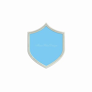 May include: A light blue shield with a white outline. The shield is a blank template for embroidery.