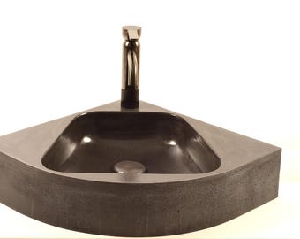 May include: A dark gray corner sink with a smooth basin and a metallic faucet centered at the back. Beside the sink are two light gray concrete cube-shaped holders, each containing a small, light-colored wooden fish sculpture.