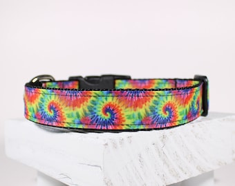 May include: A colorful tie-dye dog collar with a black buckle. The collar has a swirl pattern in shades of pink, blue, green, and yellow.
